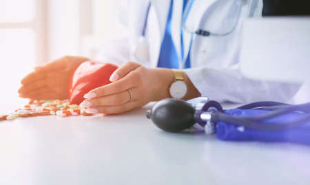 Cardiologist with red heart and stethoscope at tableの写真素材