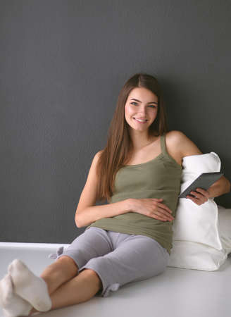 Woman sitting on the floor using a digital tabletの写真素材