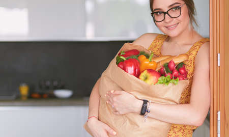 Young woman holding grocery shopping bag with vegetablesの写真素材