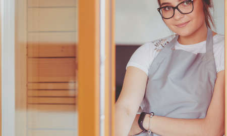 Young woman standing near desk in the kitchenの写真素材