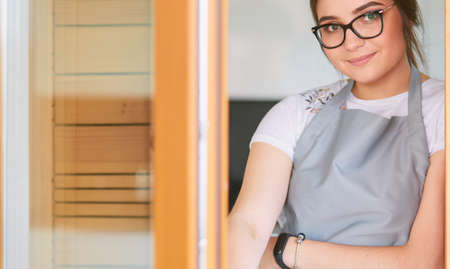 Young woman standing near desk in the kitchenの写真素材