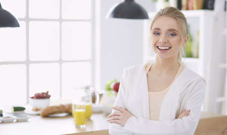Young woman standing near desk in the kitchenの写真素材