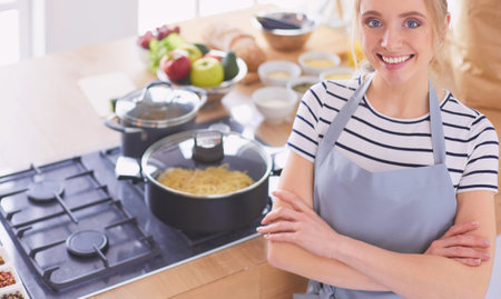 Young woman standing near desk in the kitchenの写真素材