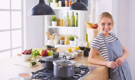Young woman standing near desk in the kitchenの写真素材