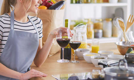 Pretty woman drinking some wine at home in kitchenの写真素材