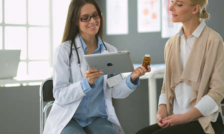 Doctor and patient discussing something while sitting at the table . Medicine and health care conceptの写真素材