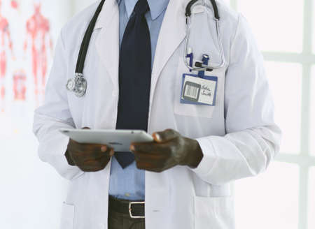 Male black doctor worker with tablet computer standing in hospitalの写真素材