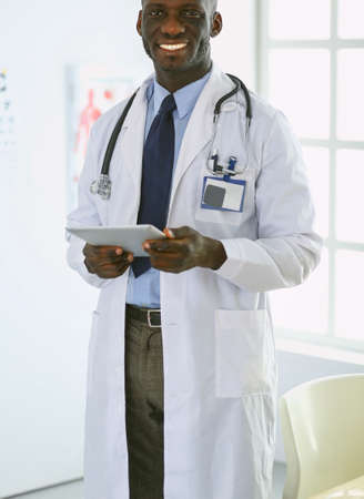 Male black doctor worker with tablet computer standing in hospitalの写真素材