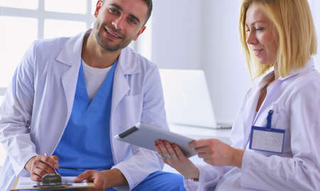 Handsome doctor is talking with young female doctor and making nの写真素材