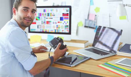 Portrait of young designer sitting at graphic studio in front of laptop and computer while working online.の写真素材
