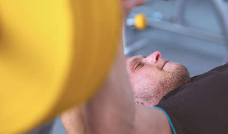 Young man lifting the barbell in gym with instructorの写真素材