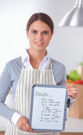 Woman in the kitchen at home, standing near desk with folderの写真素材