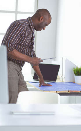 African american architect working with computer and blueprints in officeの写真素材