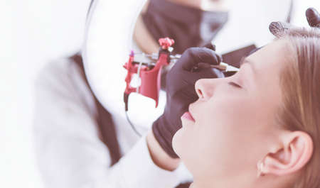 Microblading eyebrows work flow in a beauty salon. Woman having her eye brows tintedの写真素材