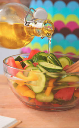 Young woman mixing fresh salad standing near deskの写真素材