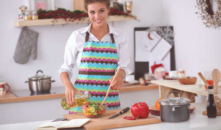 Smiling young woman mixing fresh saladの写真素材