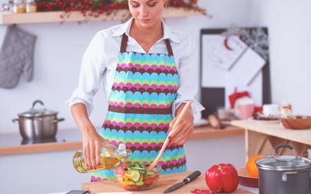 Smiling young woman mixing fresh saladの写真素材
