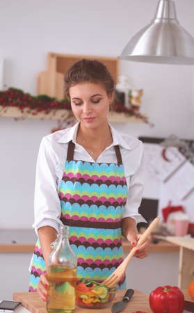 Smiling young woman mixing fresh saladの写真素材