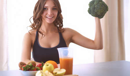 Girl sitting in kitchen on the desk with fruit and glasses juiceの写真素材