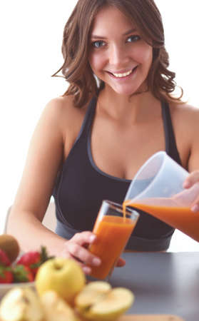 Girl sitting in kitchen on the desk with fruit and glasses juiceの写真素材