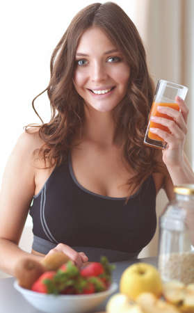 Girl sitting in the kitchen on the desk with fruit and glasses with juiceの写真素材