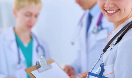 Attractive female doctor with folder in front of medical groupの写真素材