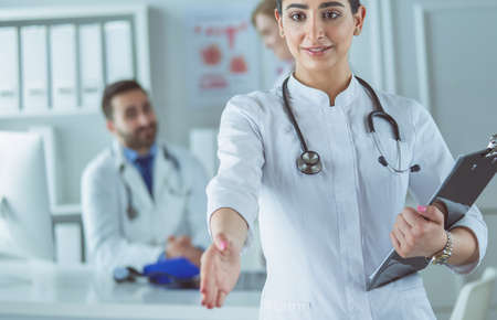 Portrait of young beautiful woman doctor giving handshakeの写真素材