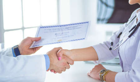 Doctor shakes hands with a patient isolated on white backgroundの写真素材