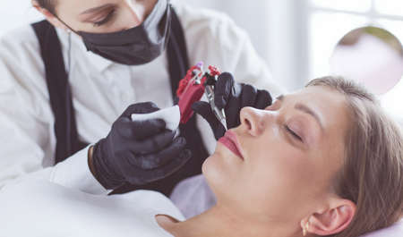 Cosmetologist applying permanent make up on eyebrowsの写真素材