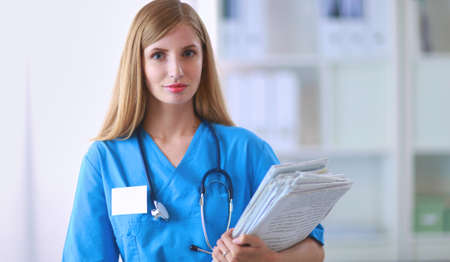 Portrait of woman doctor with folder at hospital corridorの写真素材