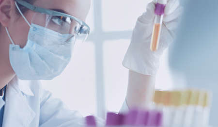 Woman researcher is surrounded by medical vials and flasks, isolated on whiteの写真素材