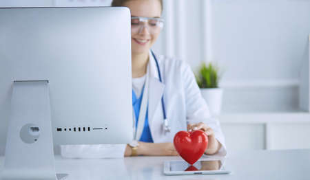 Female doctor with stethoscope holding heart, on light backgroundの写真素材