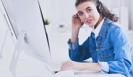 Portrait of beautiful business woman working at her desk with headset and laptopの写真素材
