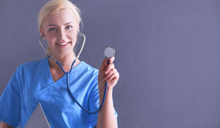 Female doctor with a stethoscope listening, isolated on gray backgroundの写真素材