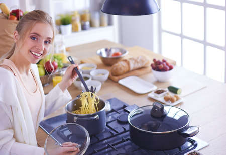 Beautiful young woman cooking in kitchen at homeの写真素材