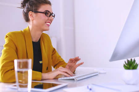 Young confident businesswoman working at office desk and typing with a laptopの写真素材