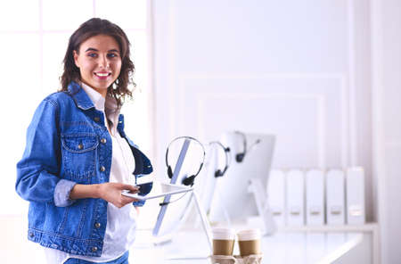 Smiling woman drinking coffee and using tablet in the cafeの写真素材