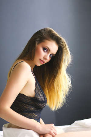 Portrait of beautiful young woman in nightwear on bedの写真素材