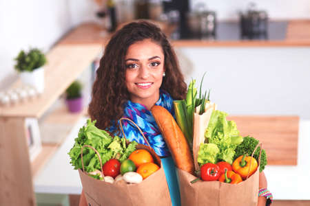 Young woman holding grocery shopping bag with vegetables Standing in the kitchen.の写真素材