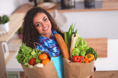 Young woman holding grocery shopping bag with vegetables Standing in the kitchen.の写真素材
