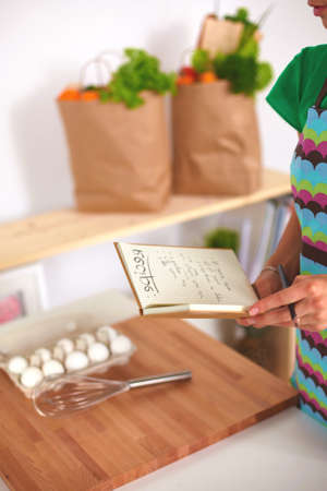 Smiling young woman in the kitchen, isolated on backgroundの写真素材