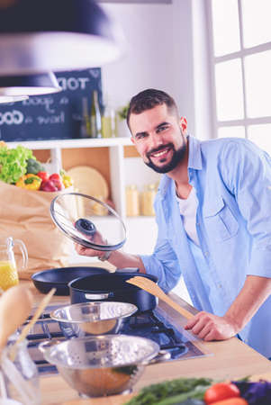 Man following recipe on digital tablet and cooking tasty and healthy food in kitchen at homeの写真素材