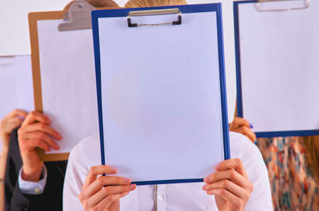 Team of businesspeople holding a folders near face isolated on white backgroundの写真素材