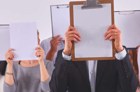 Team of businesspeople holding a folders near face isolated on white backgroundの写真素材