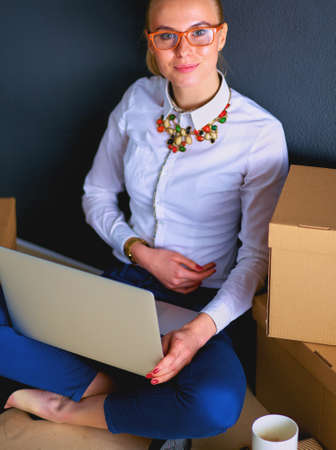 Woman sitting on the floor near a boxes with laptopの写真素材