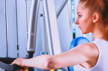 Beautiful girl at the gym exercising on trainersの写真素材