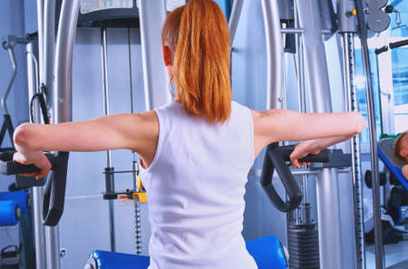 Beautiful girl at the gym exercising on trainersの写真素材