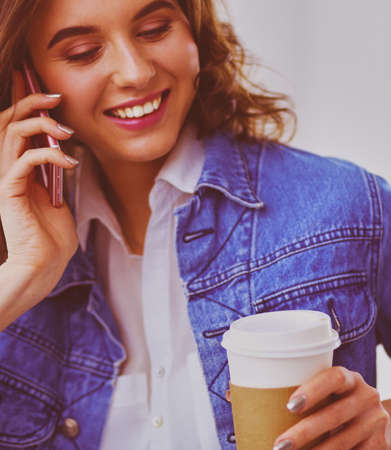 Young woman at cafe drinking coffee and talking on the mobile phoneの写真素材
