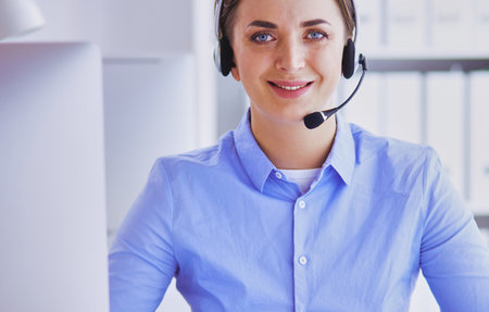 Serious pretty young woman working as support phone operator with headset in officeの写真素材