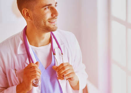 Portrait of a male doctor with laptop sitting at desk in medical officeの写真素材